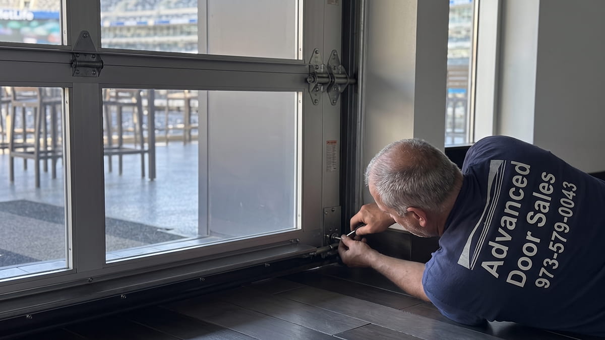 commercial garage door repair technician fixing rolling steel overhead door in New Jersey